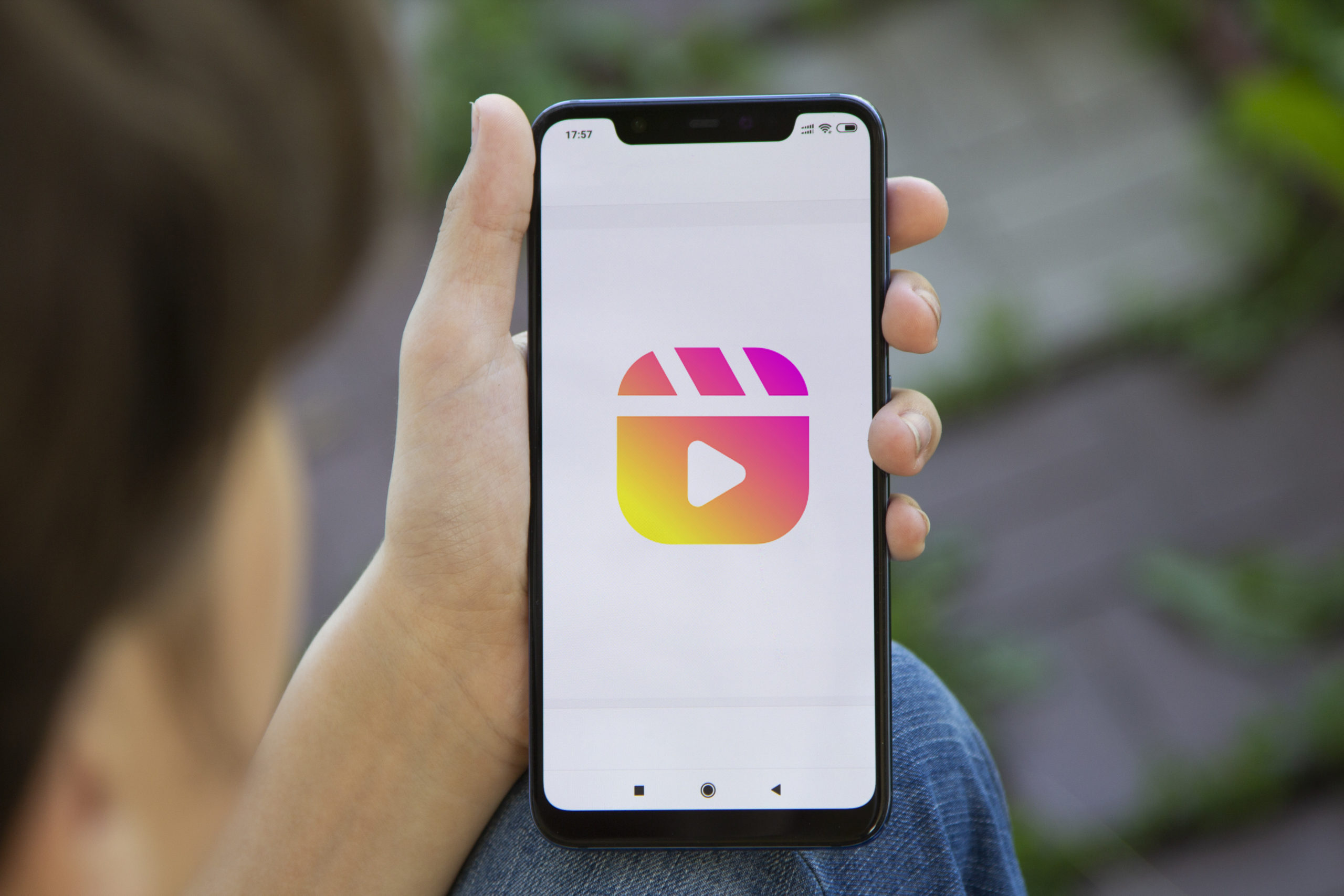 Girl hold SmartPhone displaying the Instagram reels logo. Social