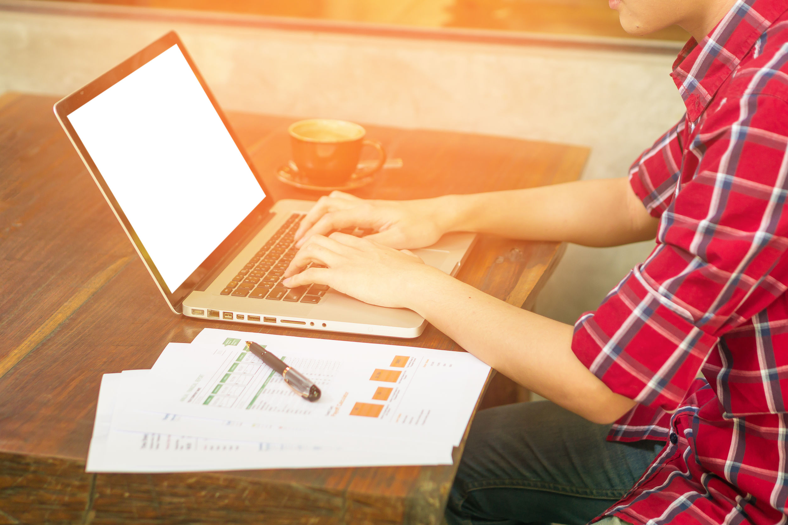 man's hands keyboarding on net-book while sitting at the wooden