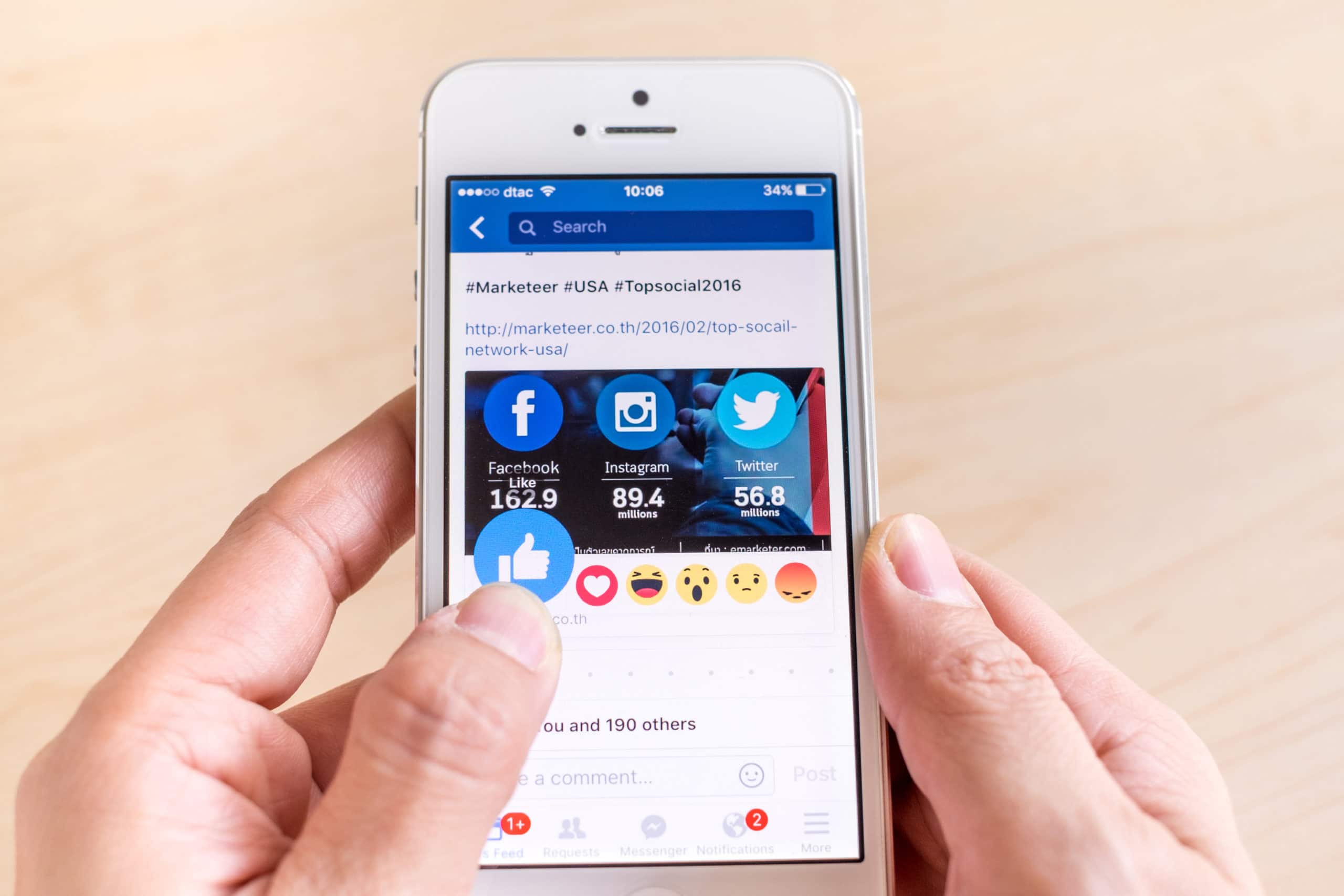 Hand holding iPhone with New facebook like button (6 emoji) on screen ,Social media are using for information sharing and networking
