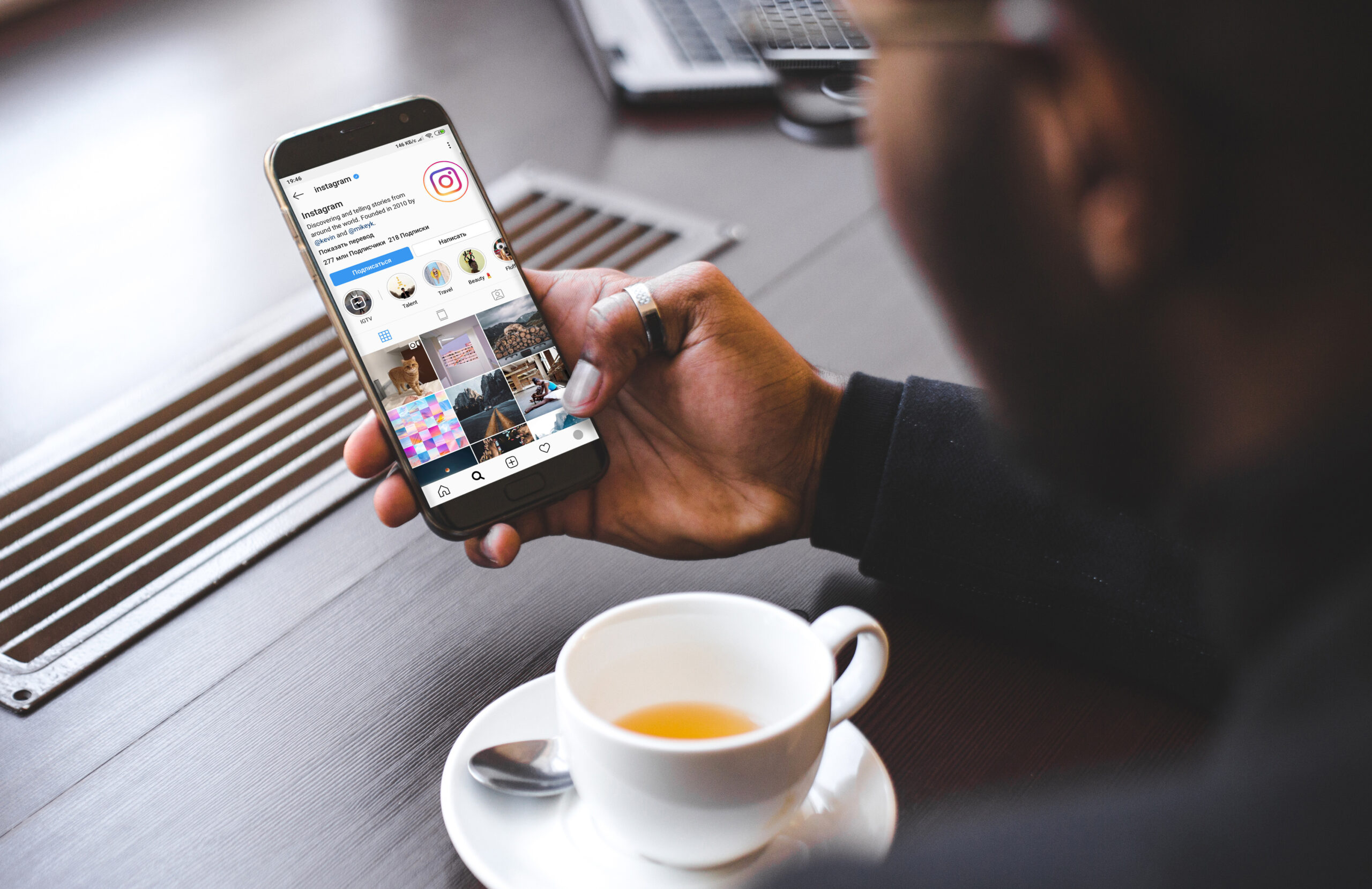 African American man sitting in a cafe, drinking coffee and working behind a mobile phone. Mock up screen