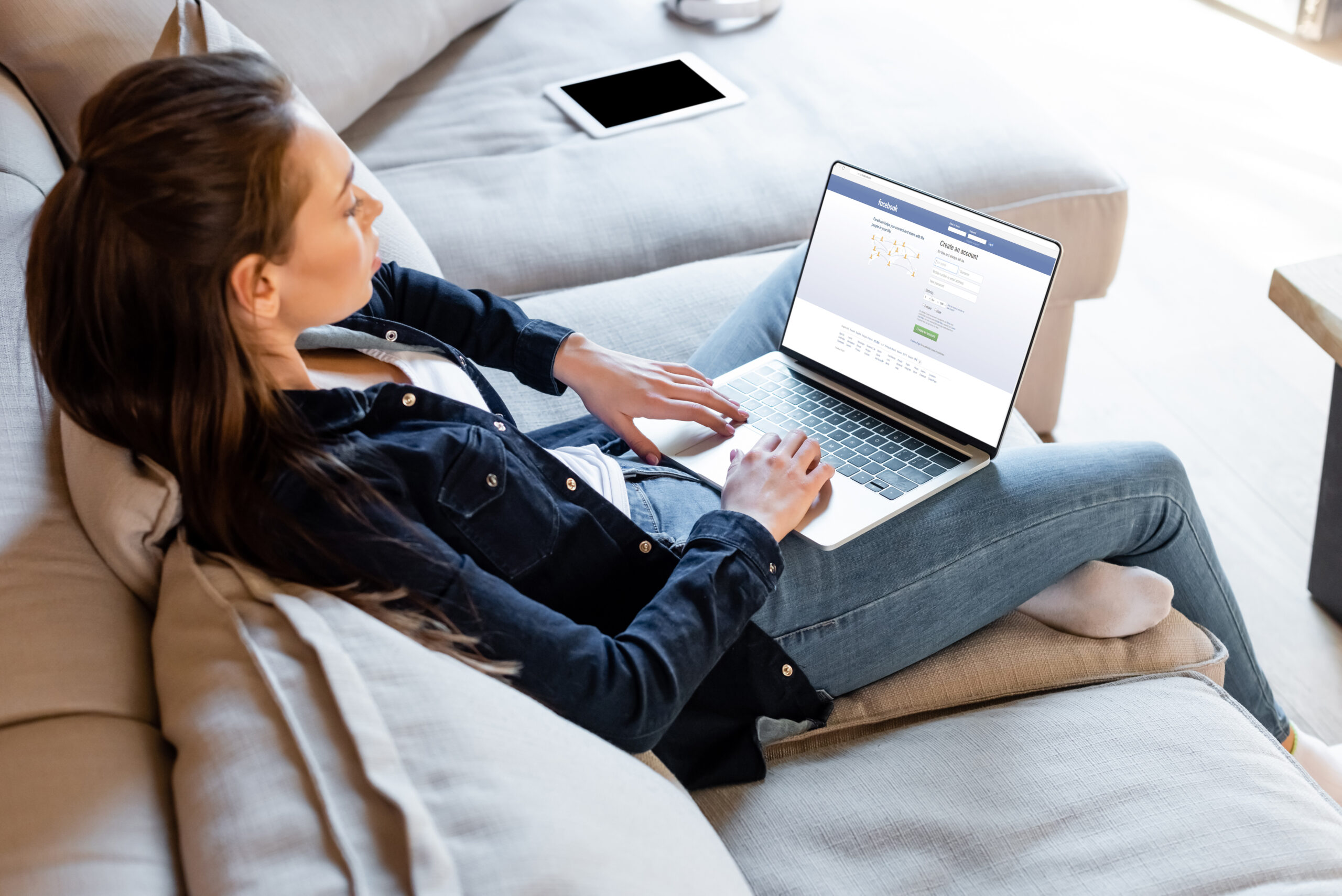 selective focus of freelancer using laptop with facebook website near digital tablet with blank screen
