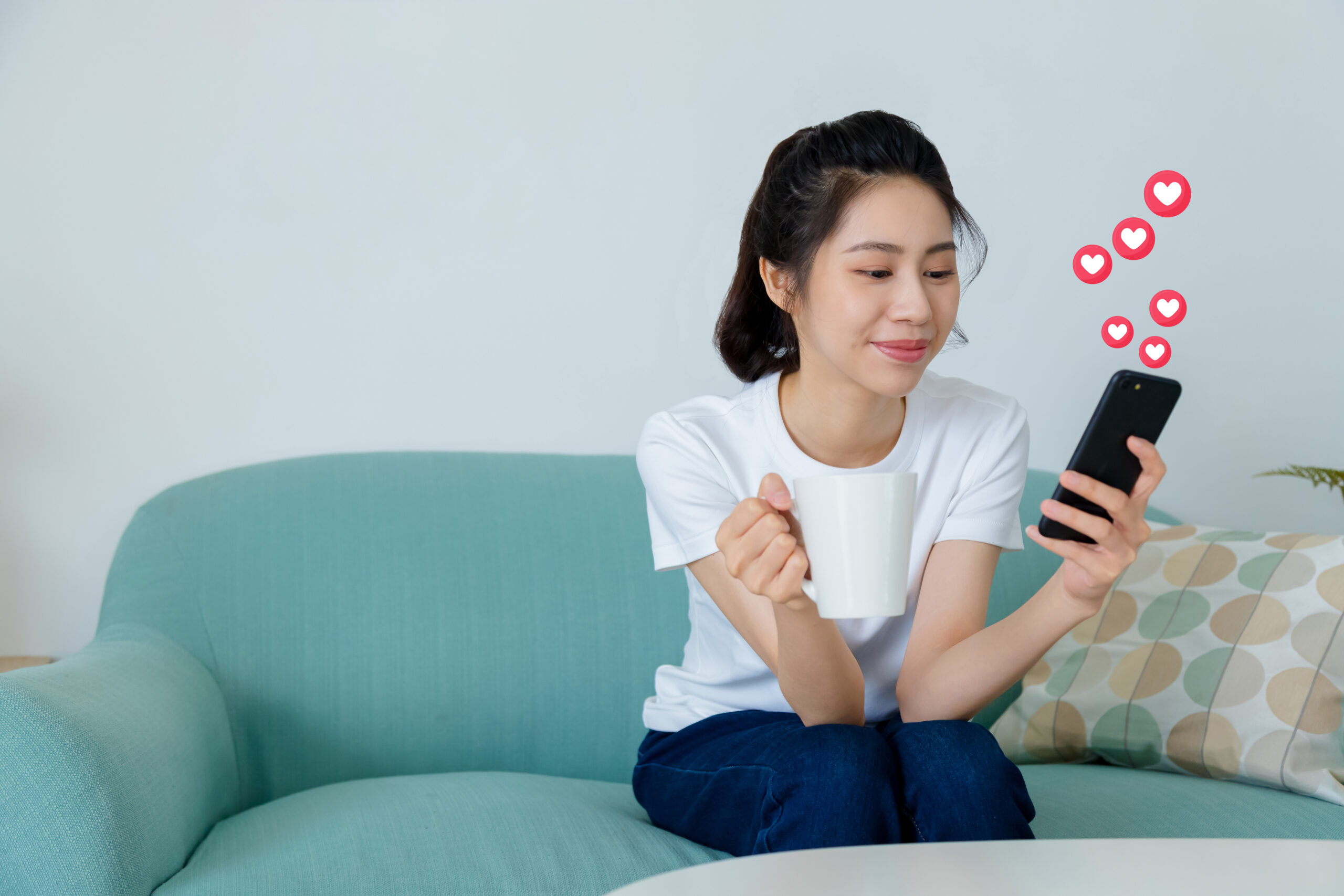 Young asia woman with ponytail in white t-shirt using social media on mobile phone in the morning